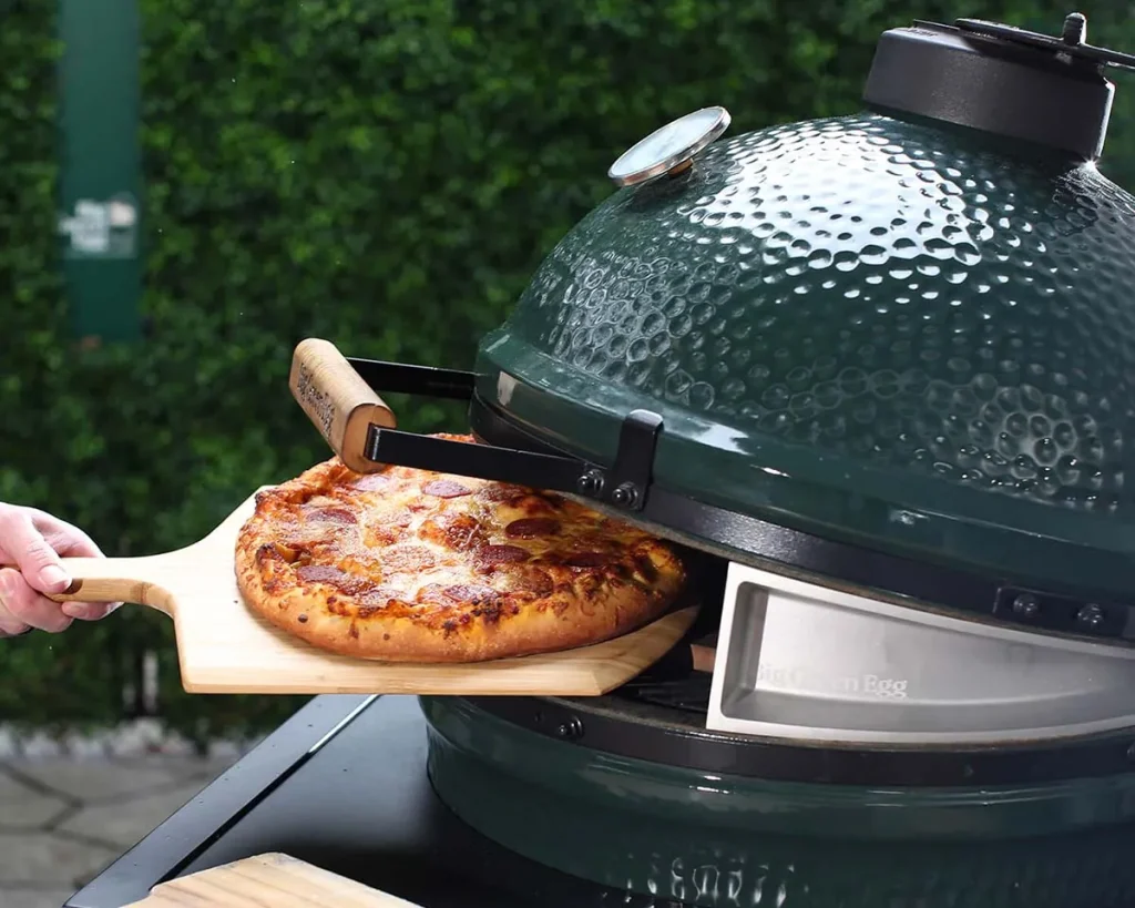 Big Green Egg converted into a pizza oven with a perfect homemade pizza being removed